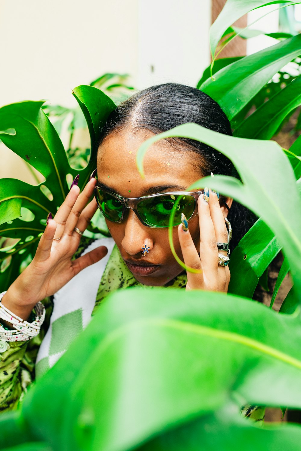 a woman wearing sunglasses and holding her hands to her face