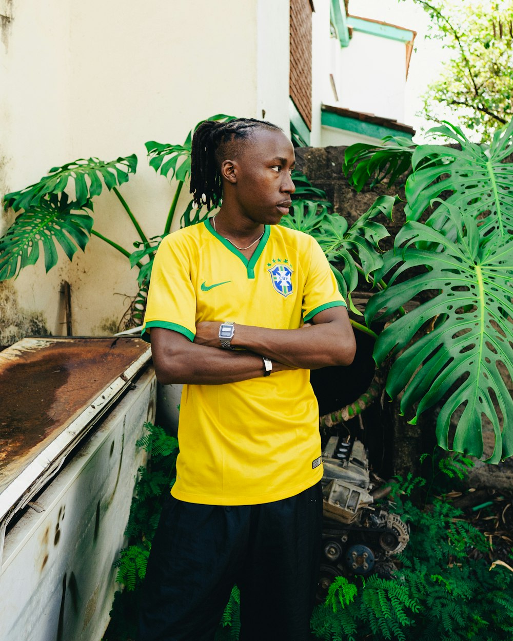 a man in a yellow shirt standing in front of a plant