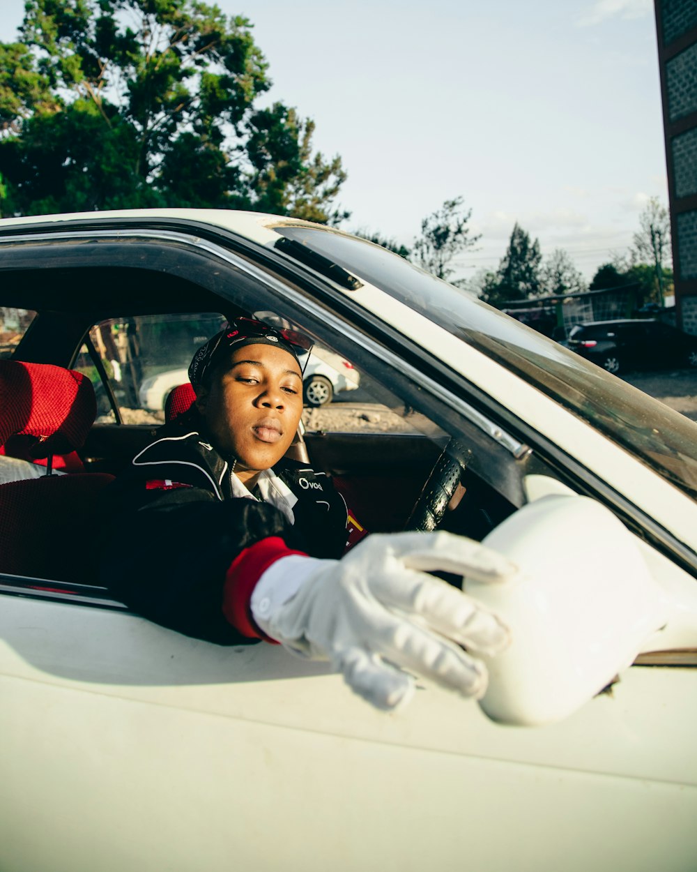 a woman sitting in a car with gloves on