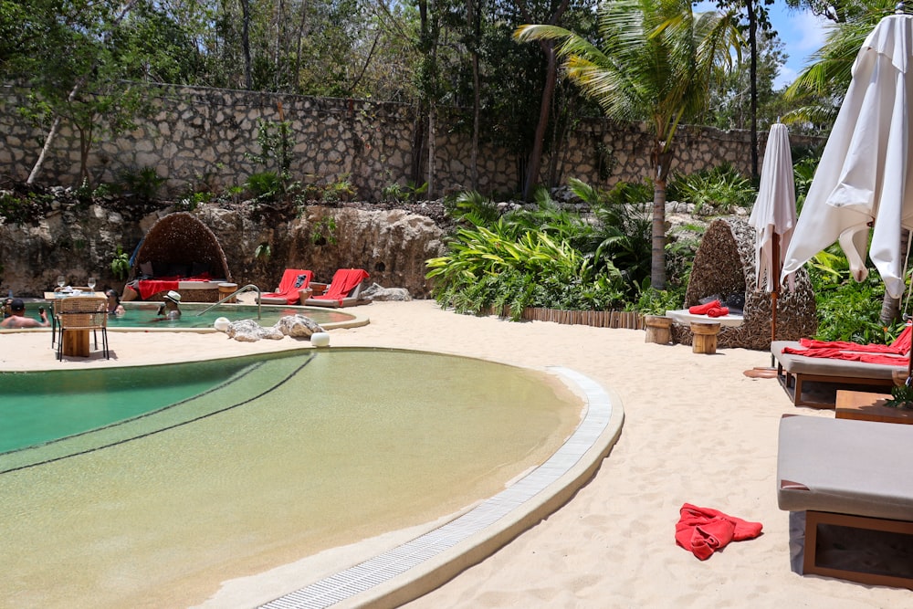 a pool with lounge chairs and umbrellas next to it