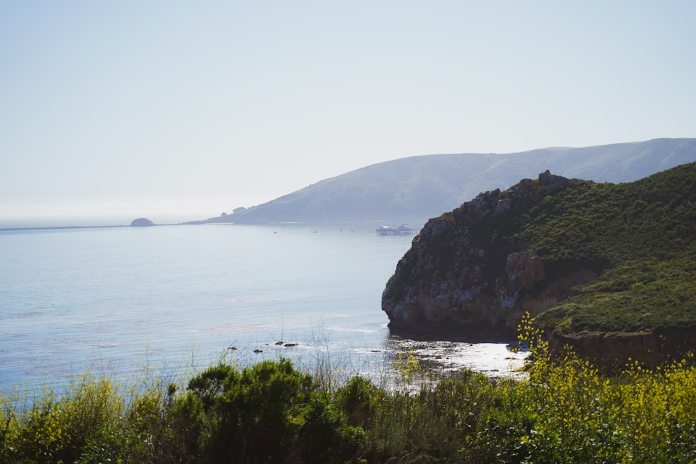 a large body of water surrounded by a lush green hillside