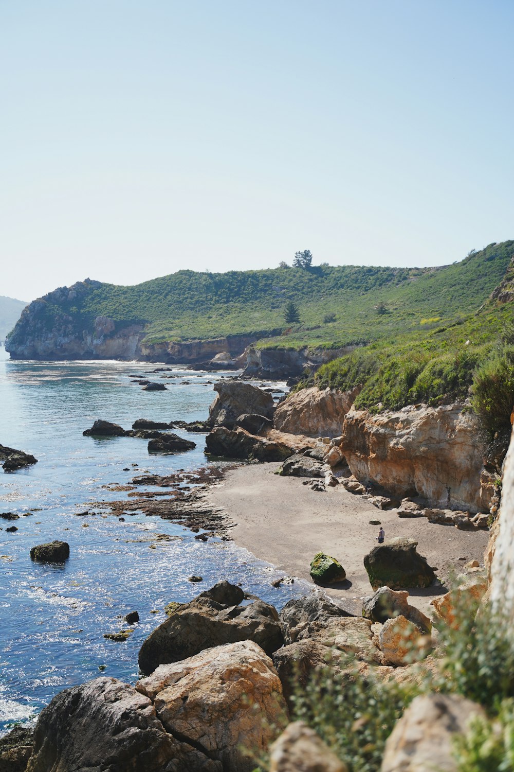 a view of a rocky beach with green hills in the background