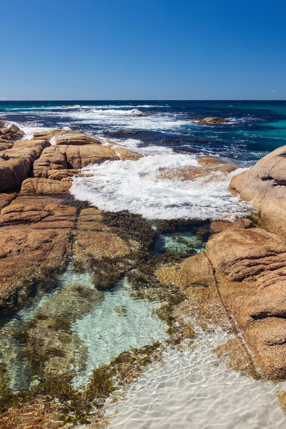 a rocky beach with clear blue water