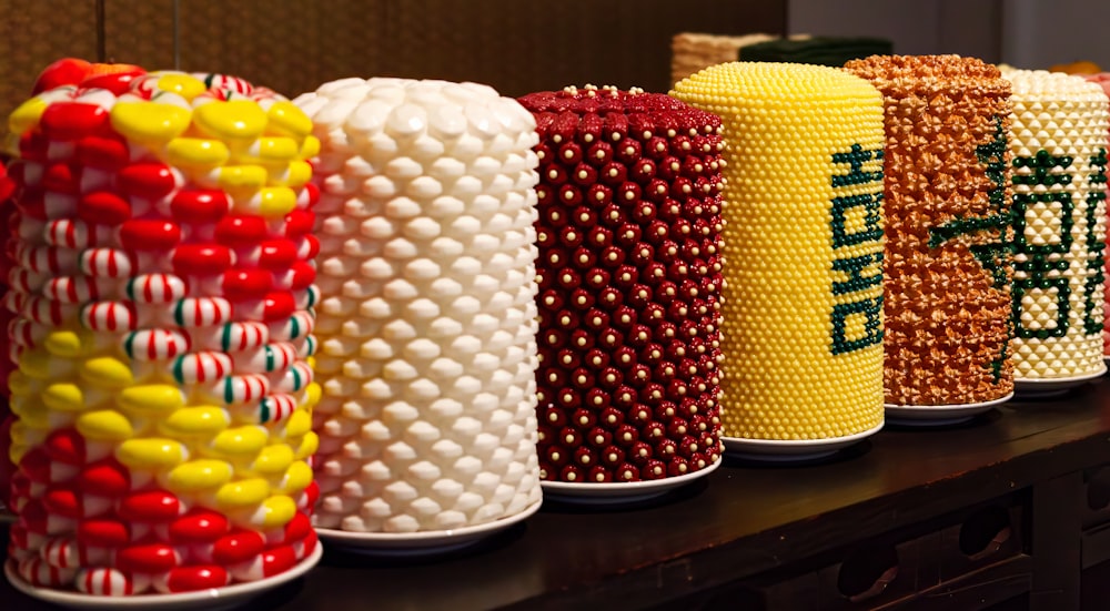 a row of candy covered vases sitting on top of a table