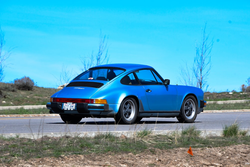 a blue car is driving down the road