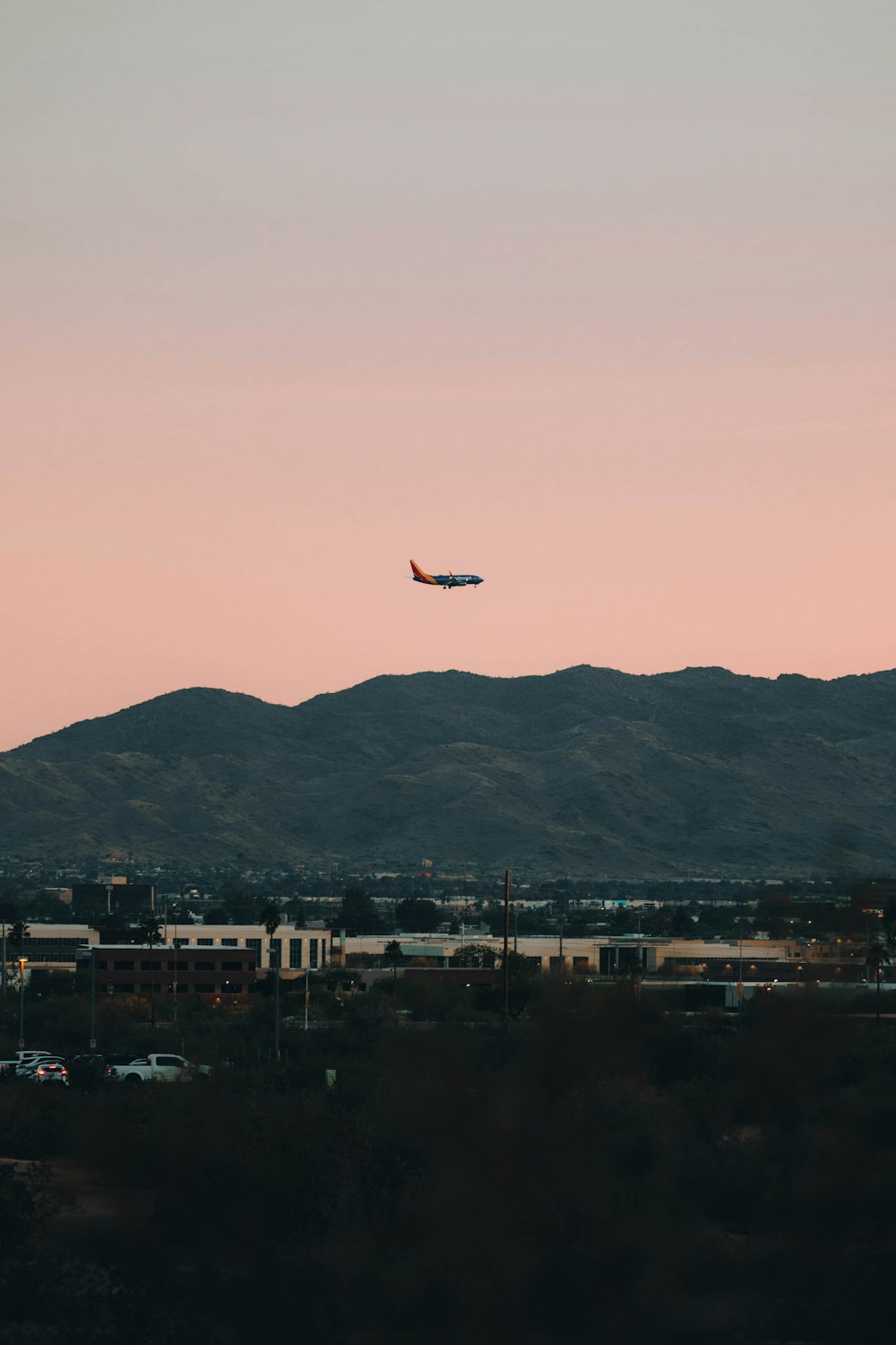 a plane flying over a city with mountains in the background