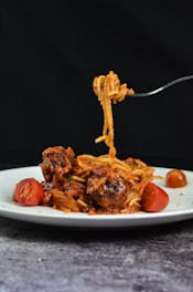 a white plate topped with spaghetti and meat