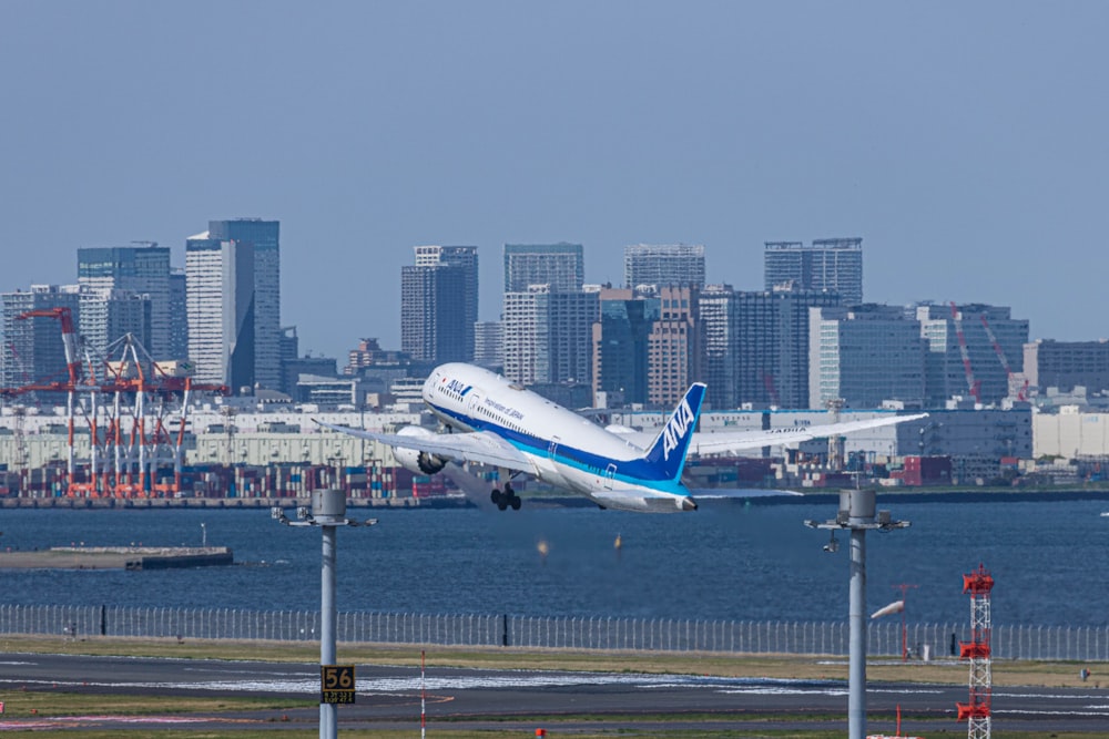 a large jetliner flying over a city next to a body of water