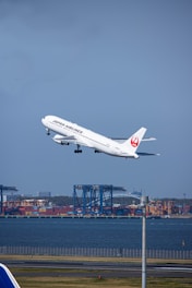 a large jetliner flying over a body of water