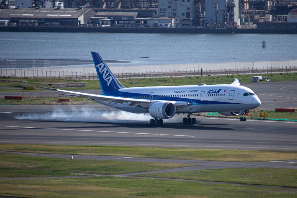 a blue and white jet airliner taking off from an airport runway