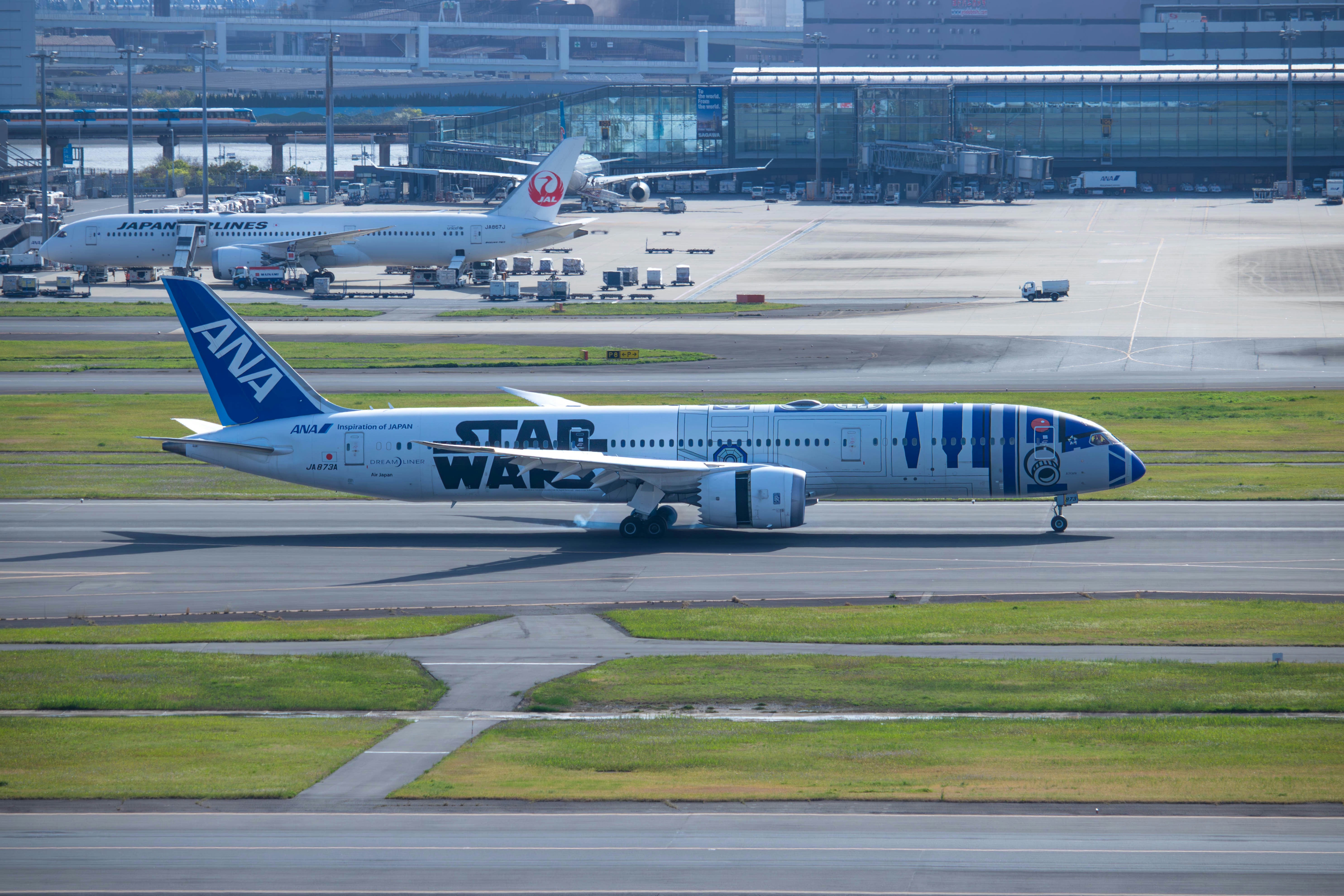 a blue and white jet airliner sitting on top of an airport runway, 