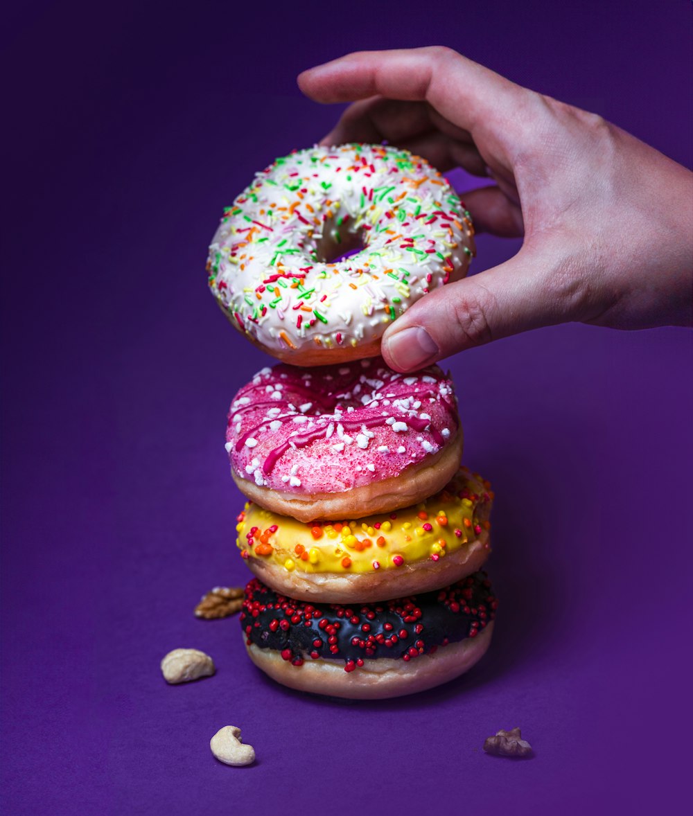 a hand reaching for a donut with sprinkles on it