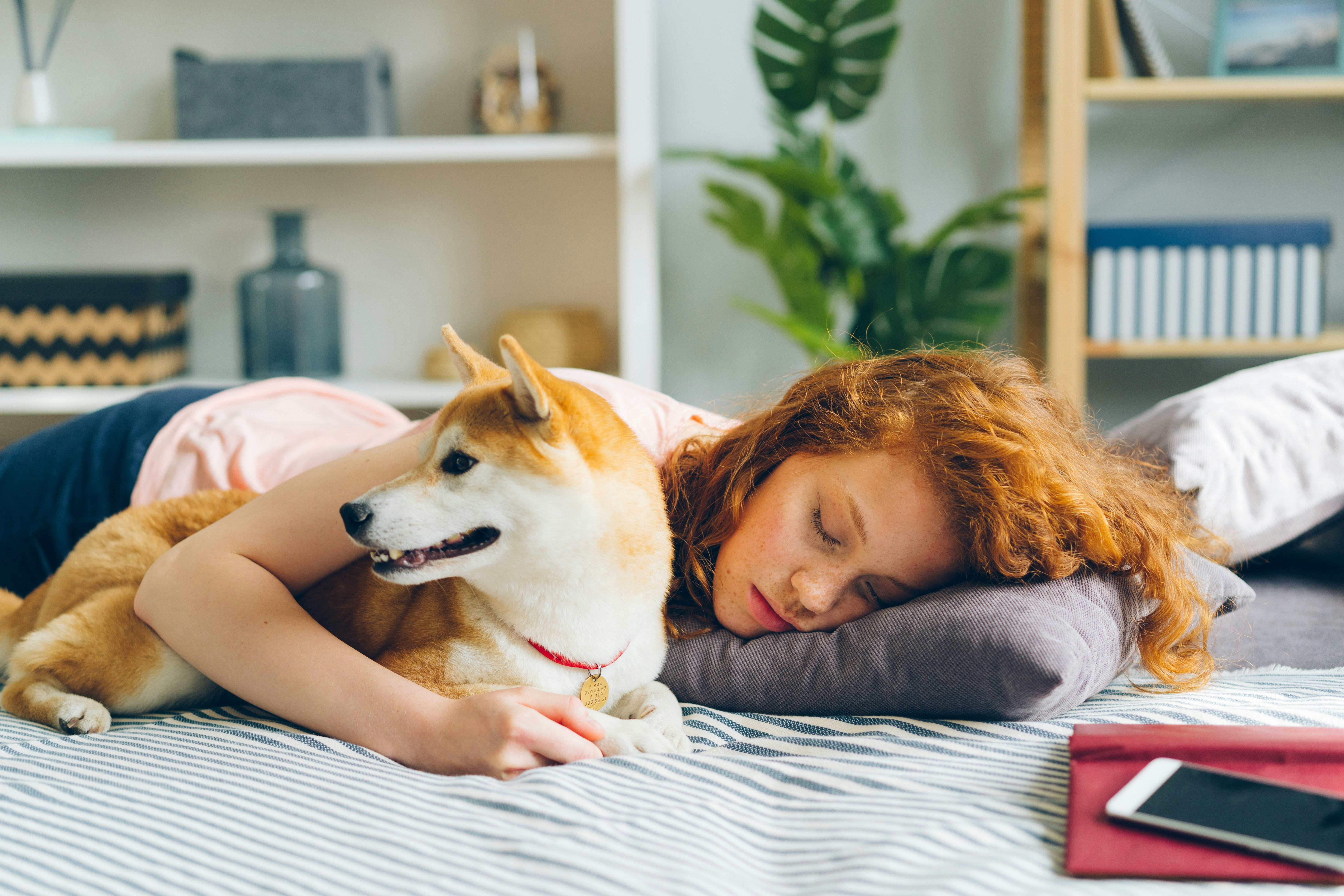 a woman laying on a bed with a dog