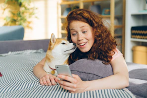 a woman laying on top of a bed next to a dog