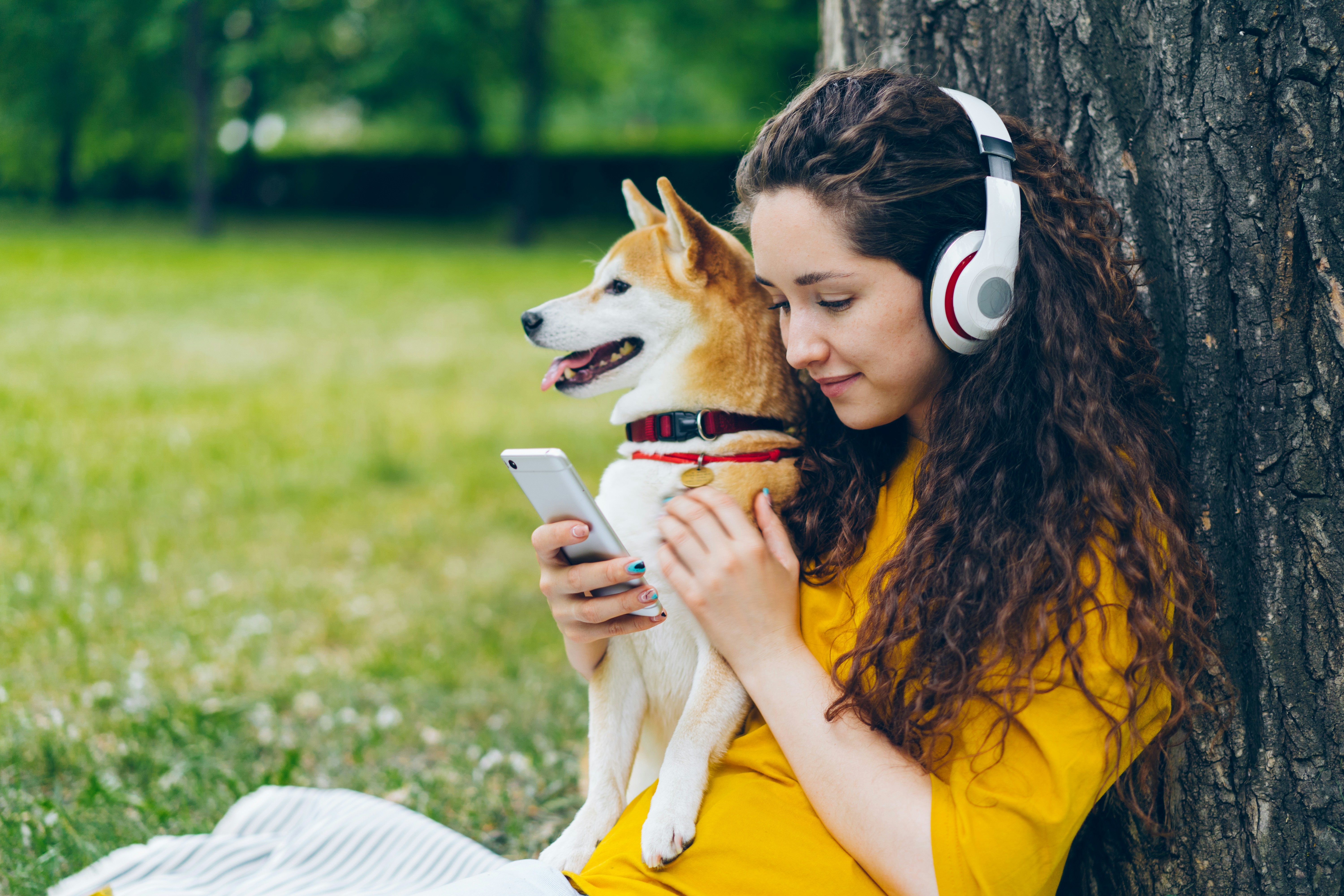 a woman with headphones is holding a dog
