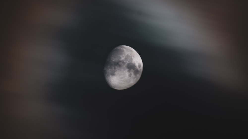 a full moon is seen through the clouds