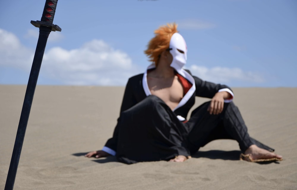 a person sitting in the sand with a mask on