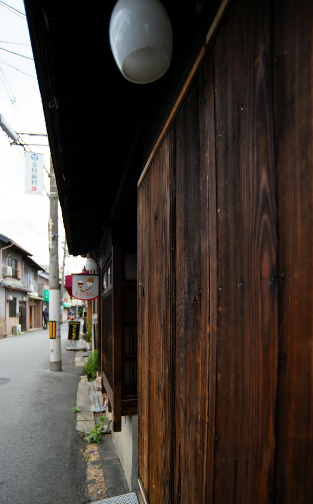 a wooden building with a white light hanging from it's side