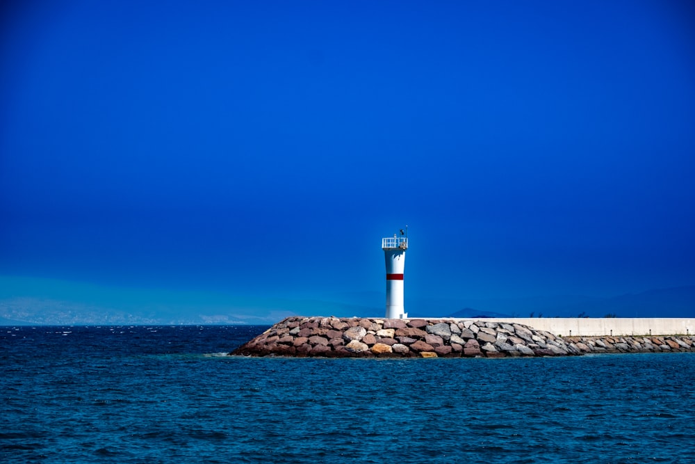 a lighthouse on a rock outcropping in the middle of the ocean