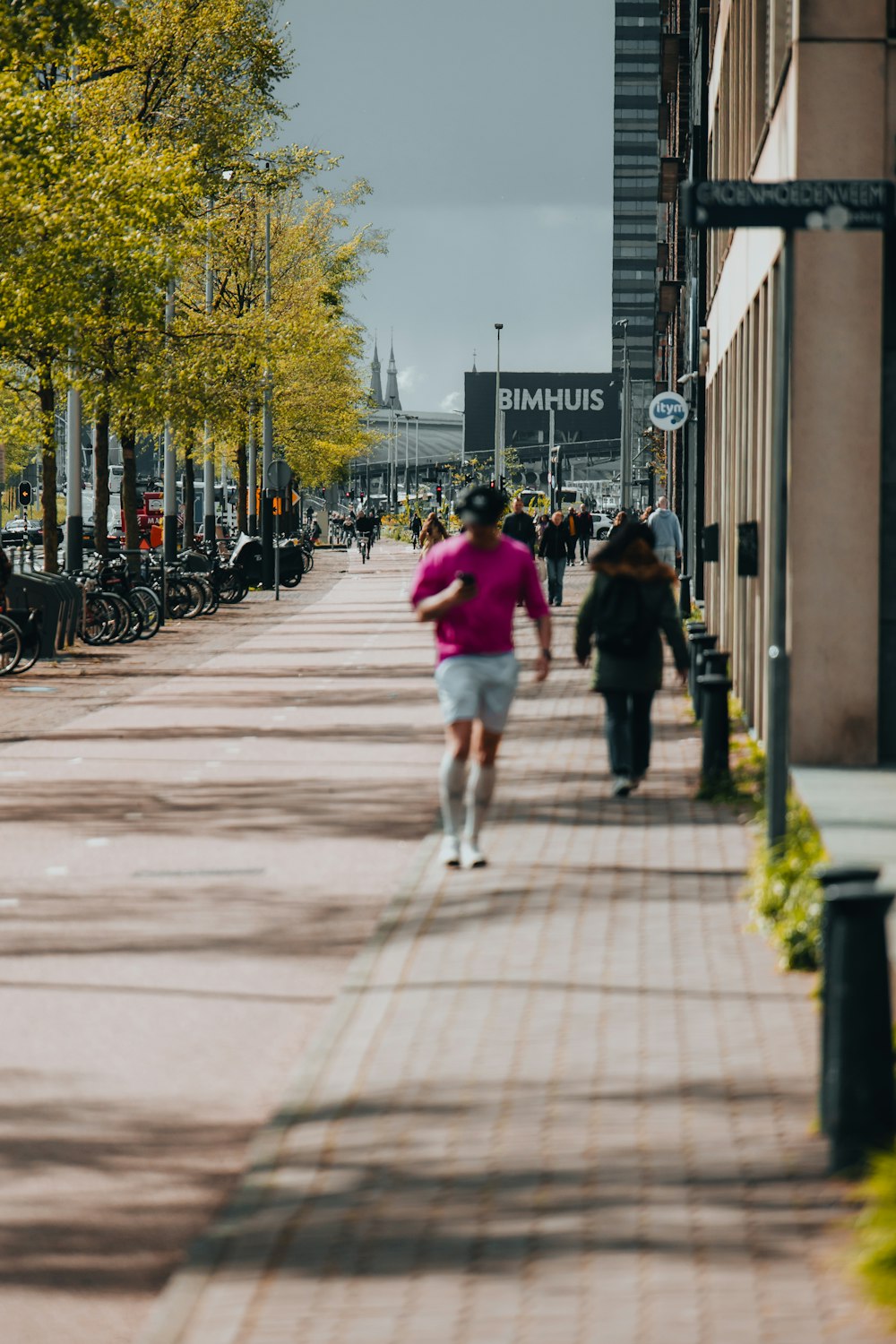 a woman in a pink shirt running down a sidewalk