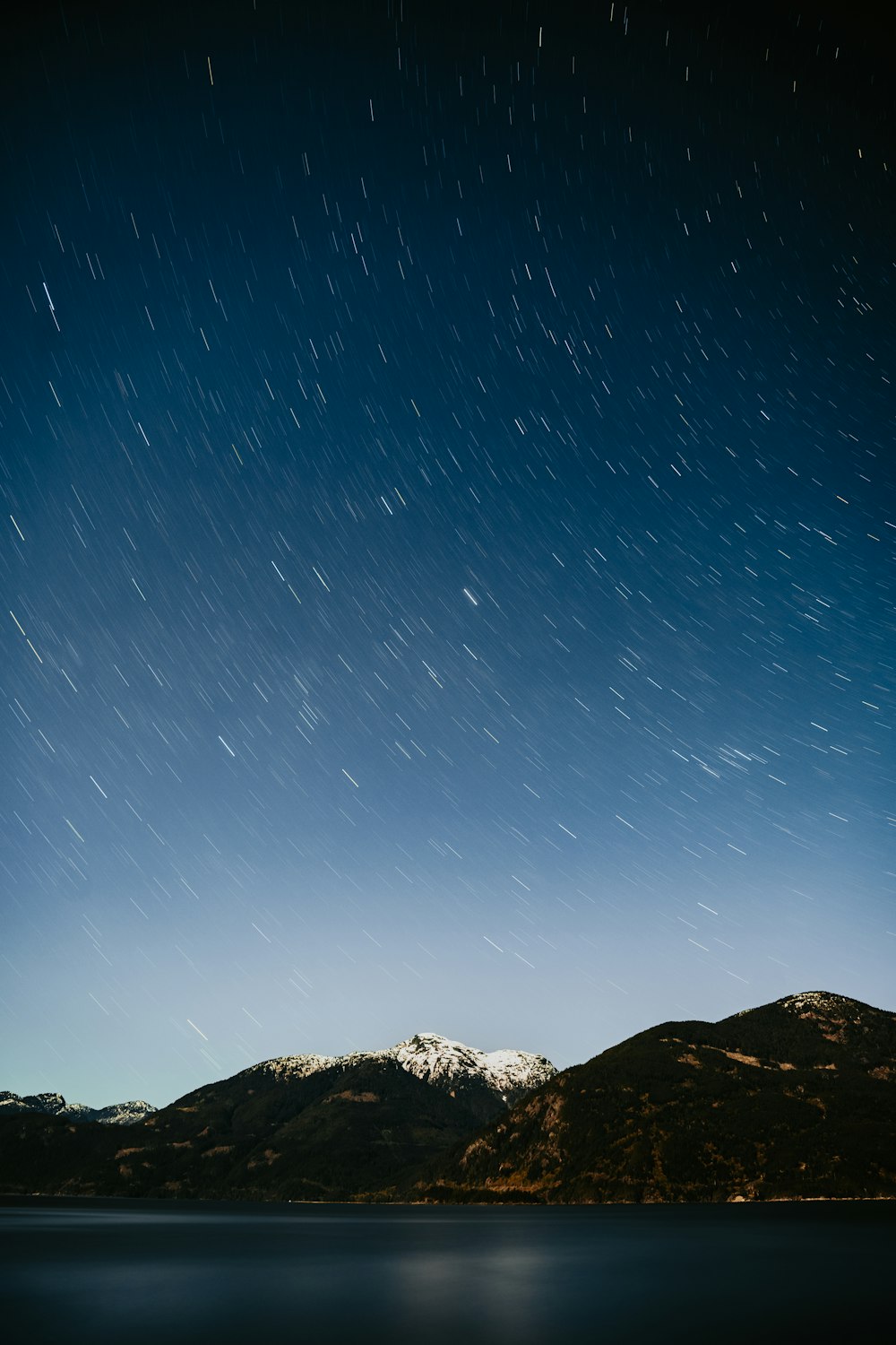 the night sky over a mountain range and a body of water