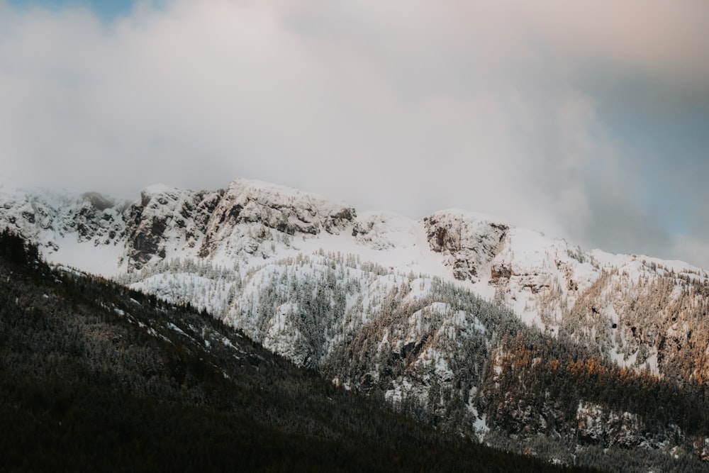 a mountain covered in snow under a cloudy sky