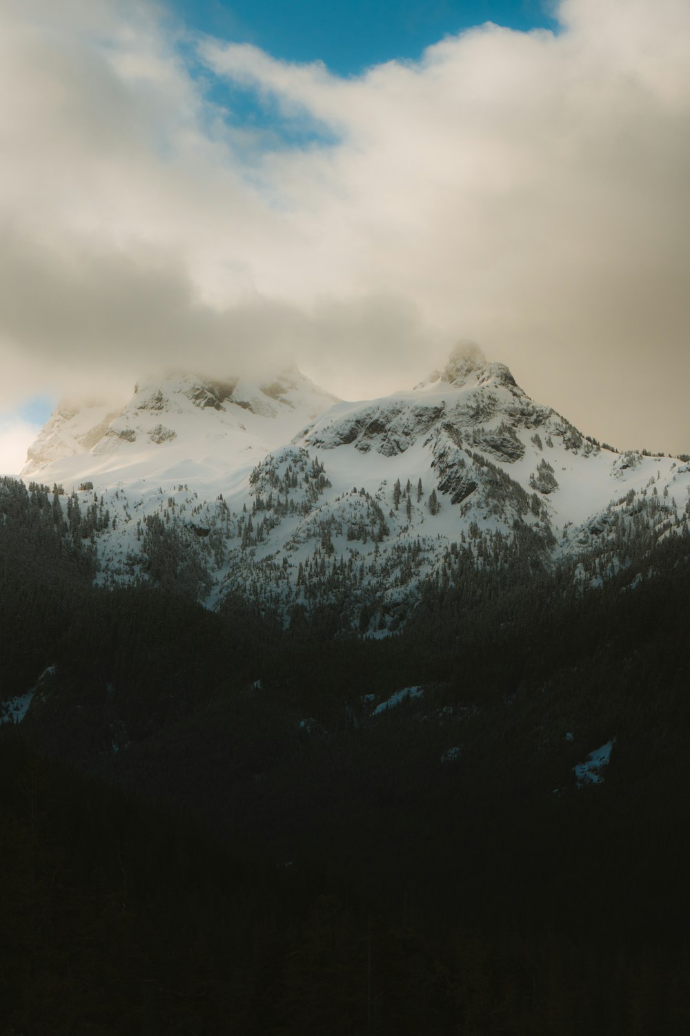 a mountain covered in snow under a cloudy sky