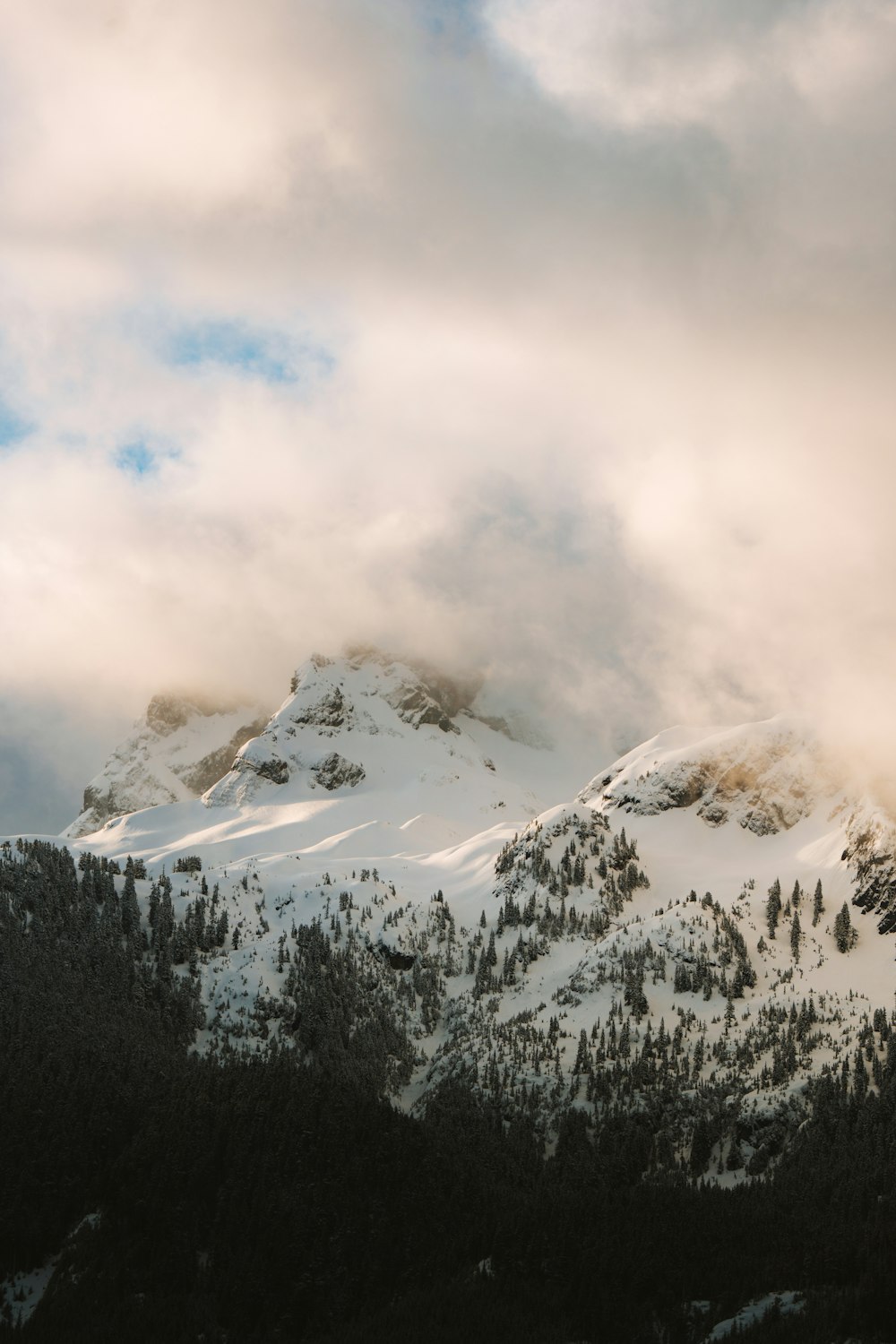 a snow covered mountain under a cloudy sky