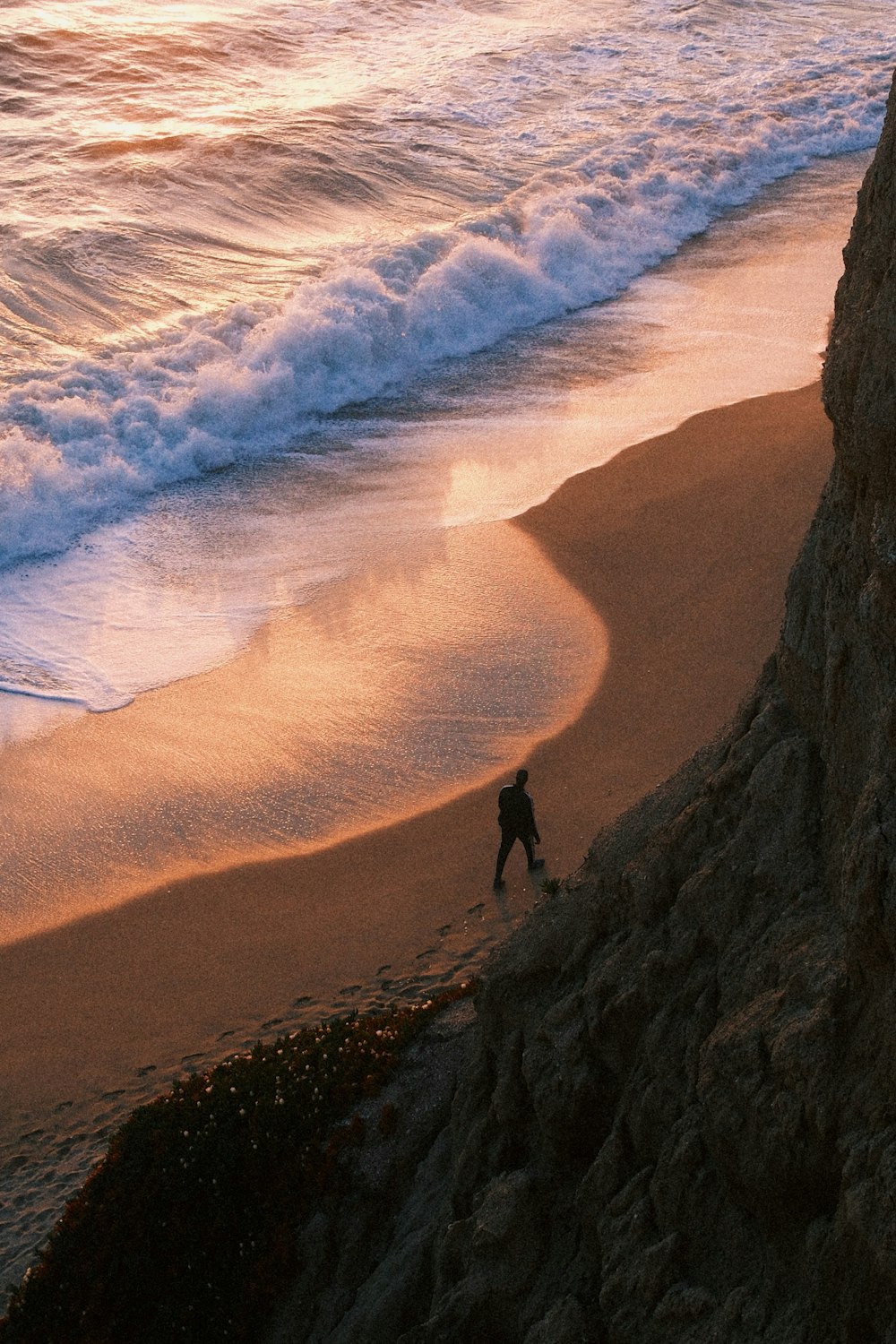 a person walking on a beach next to the ocean