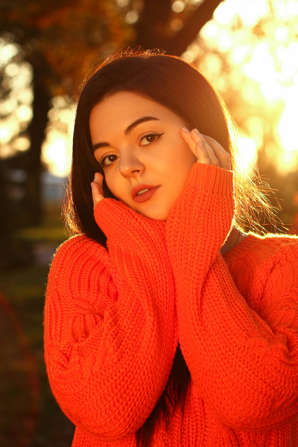 une femme dans un pull orange posant pour une photo