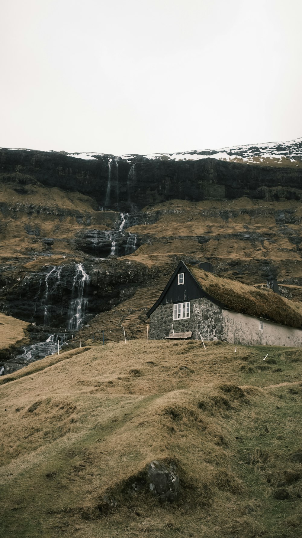 a house on a hill with a waterfall in the background