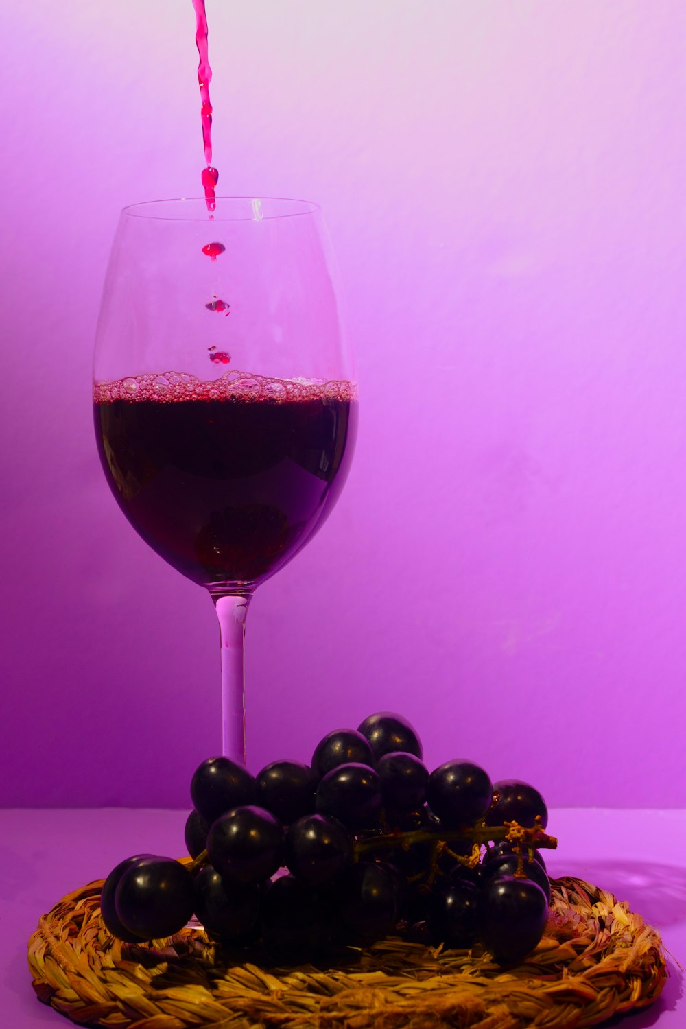 a glass of red wine being poured into a glass