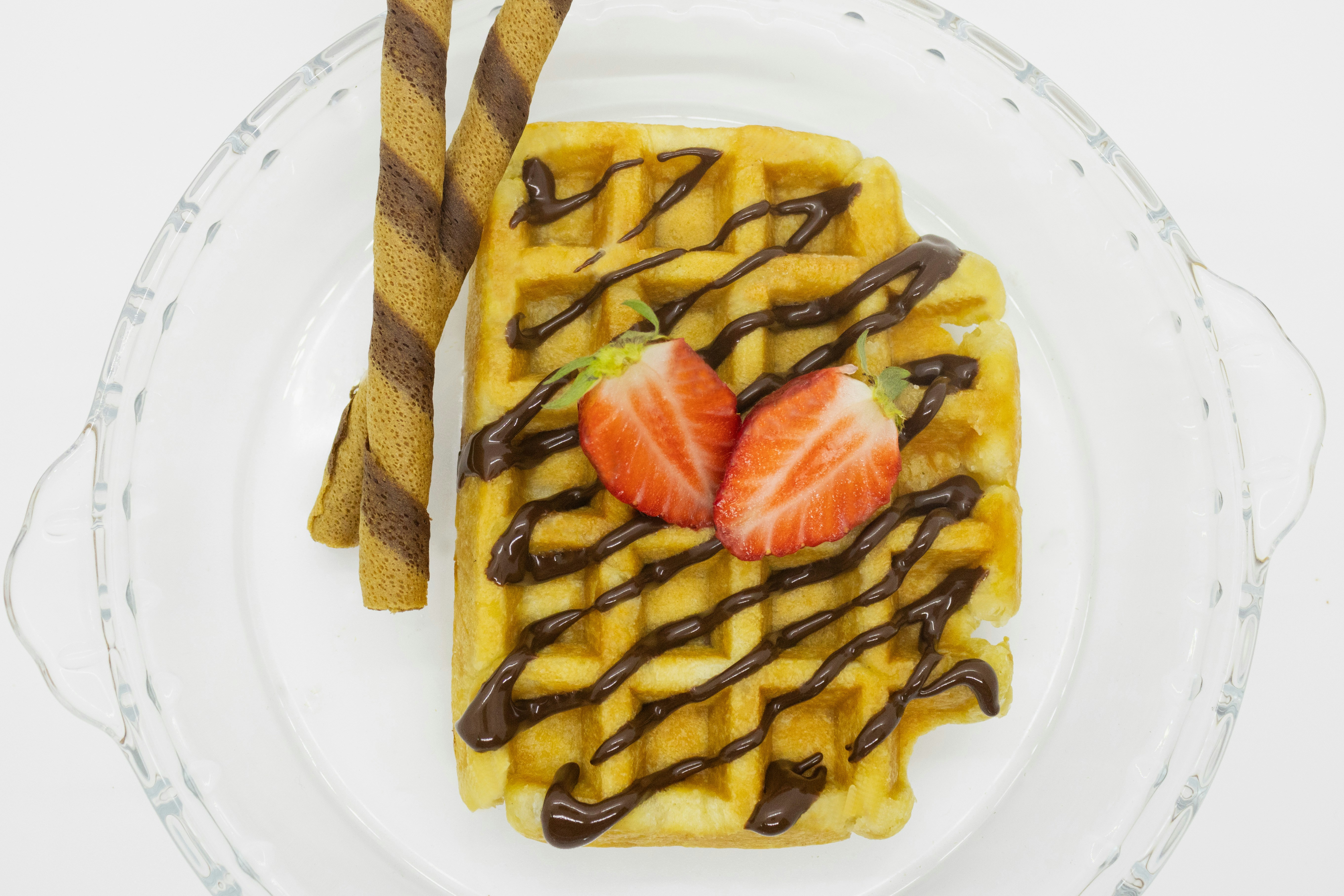 a waffle topped with strawberries and chocolate drizzled