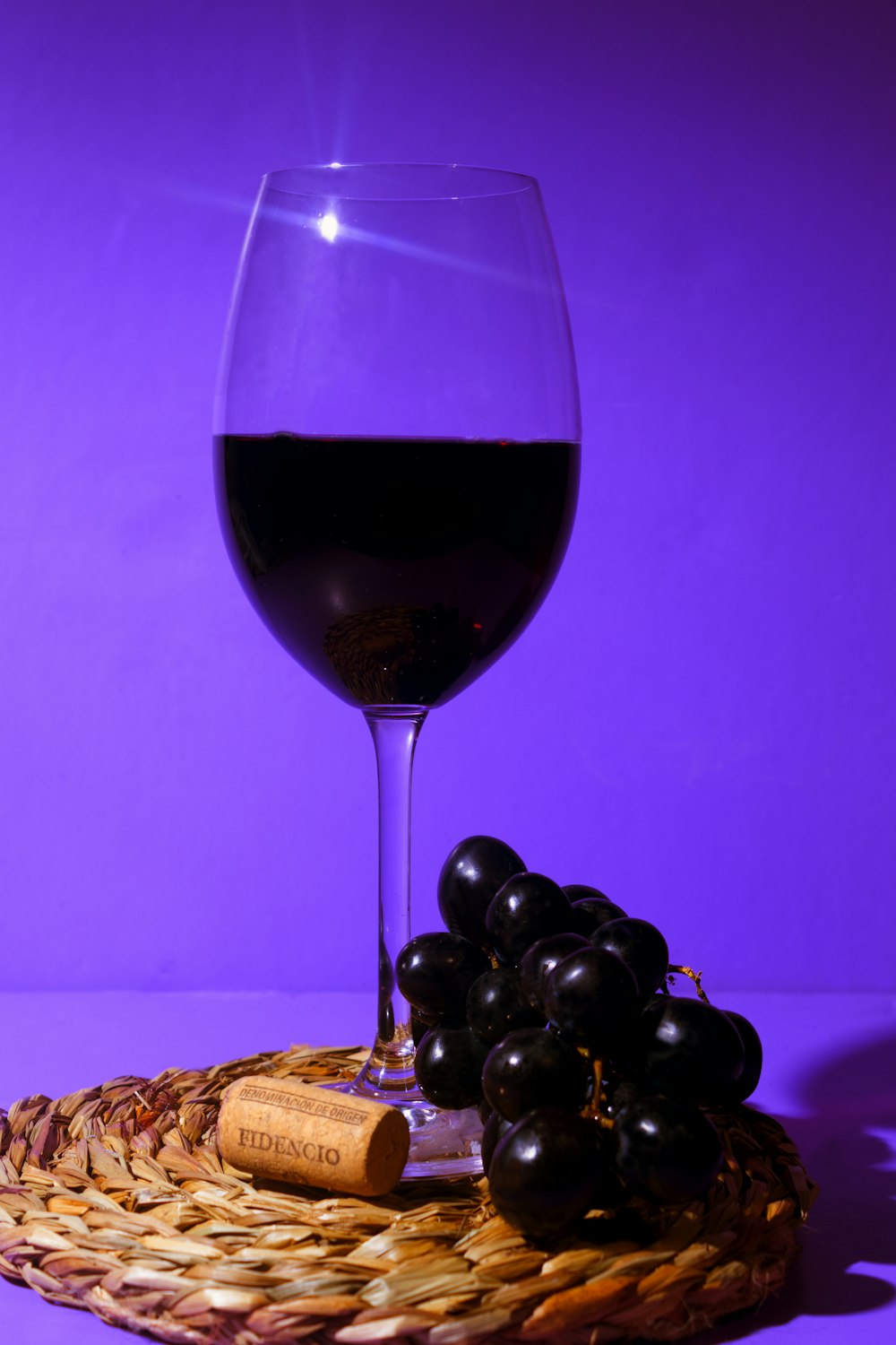 a glass of wine and some grapes on a wicker basket