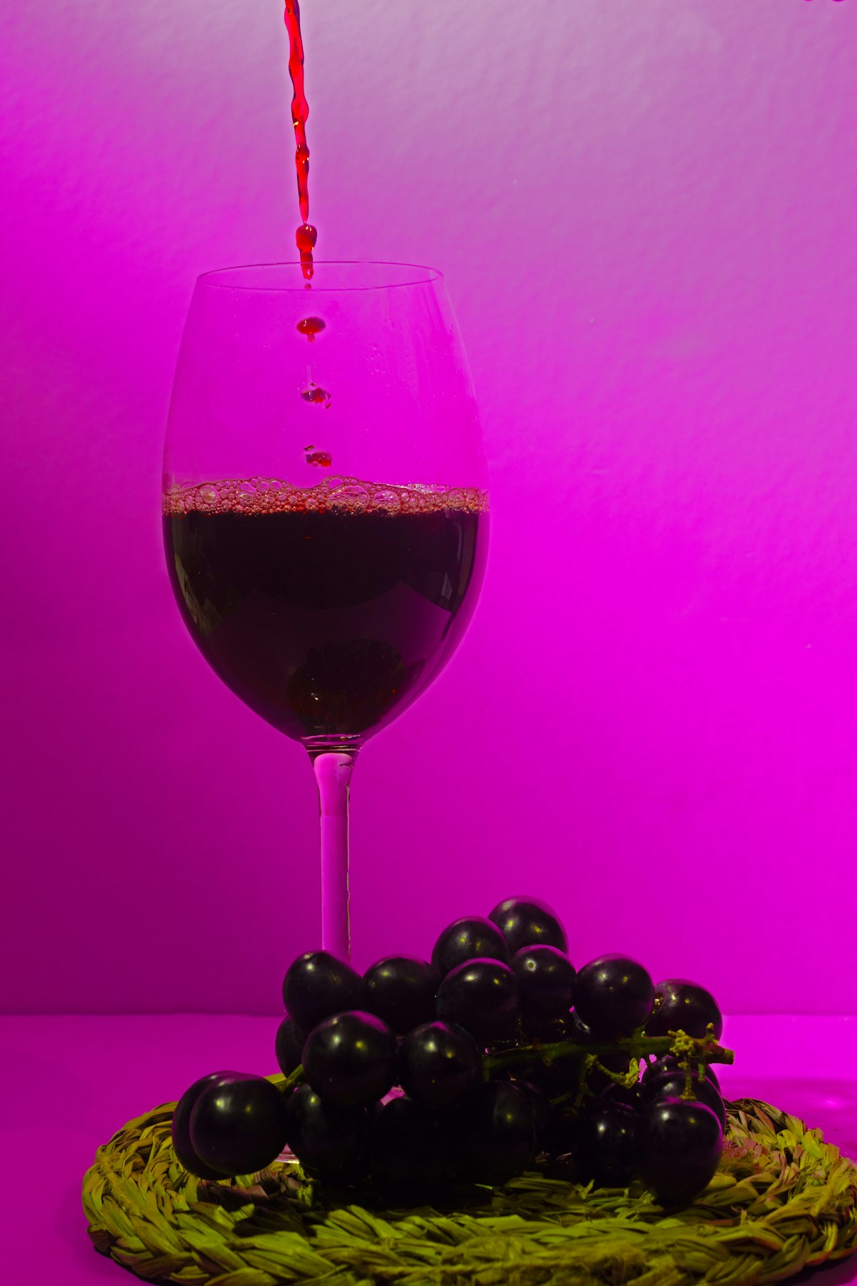 Deep red wine pouring into a glass, its color echoing Grenache's bright fruit