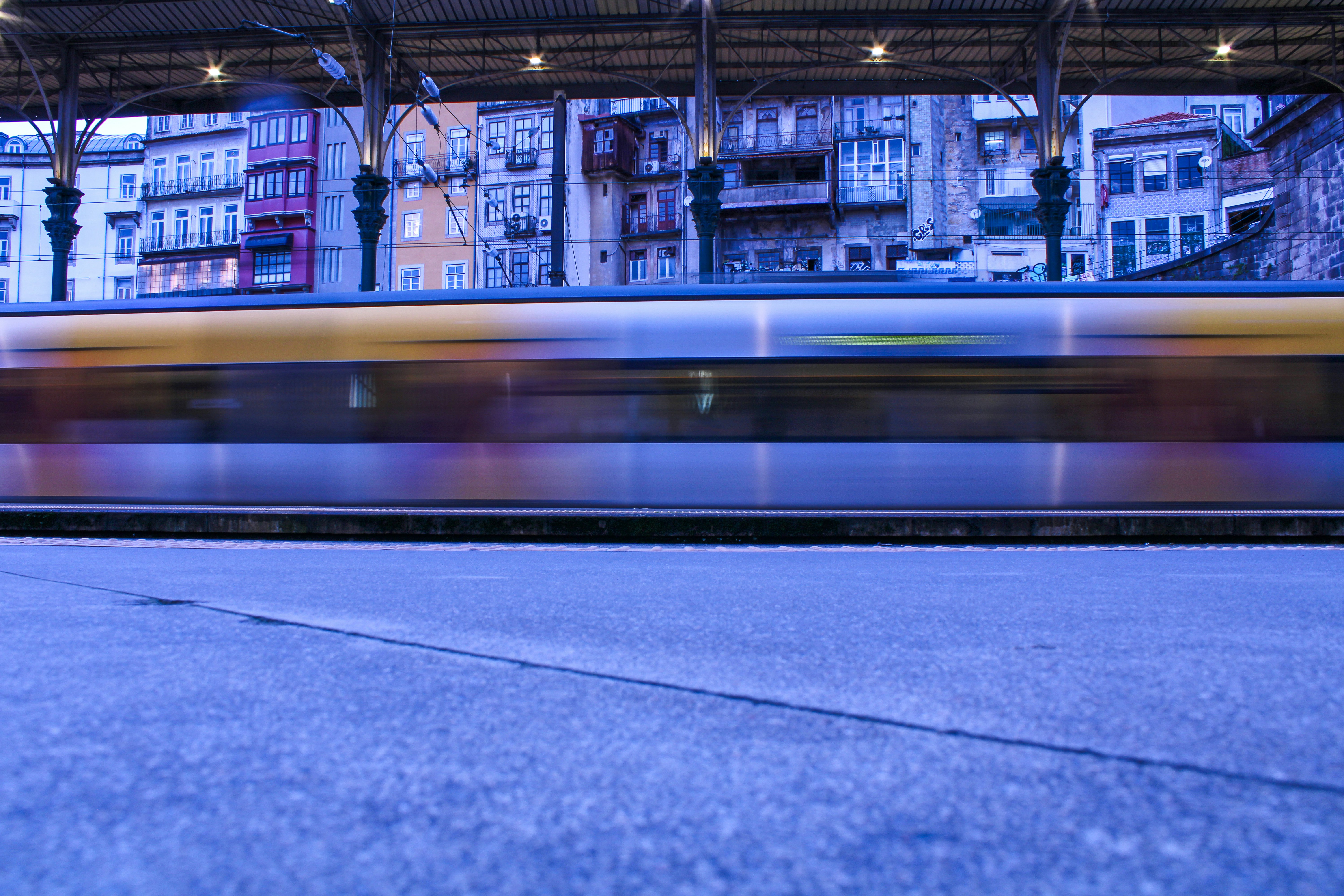 a train traveling past a train station next to tall buildings