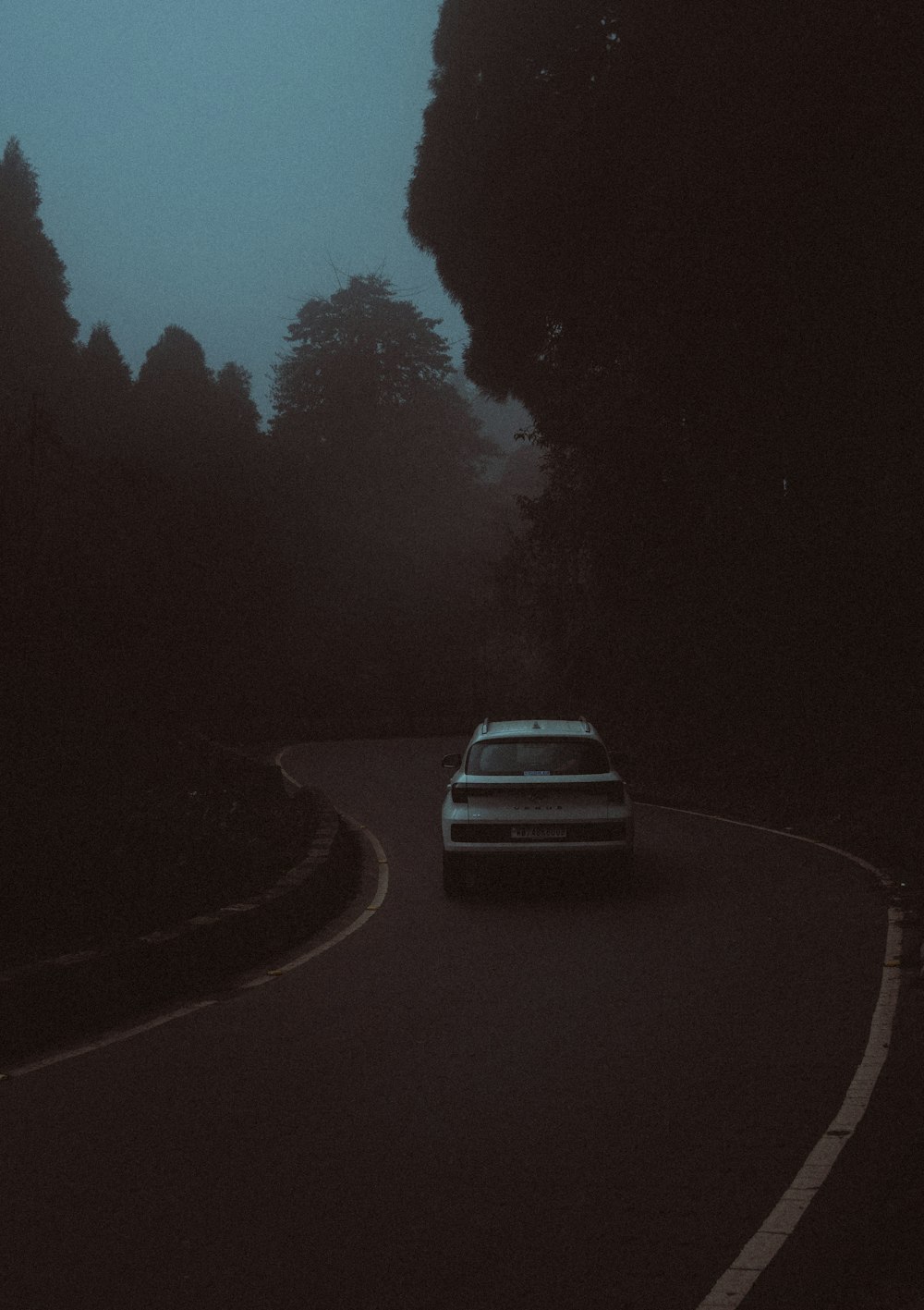 a car driving down a road in the dark