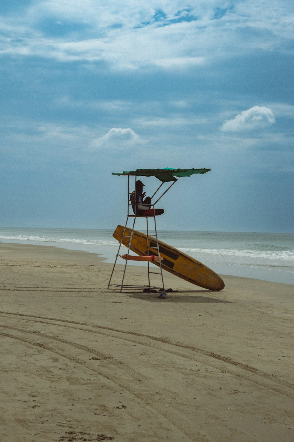 a lifeguard stand with a surfboard on the beach