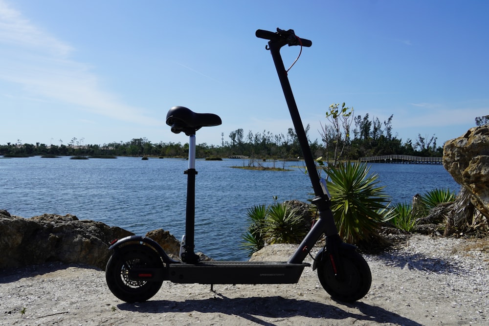 a scooter parked on a beach next to a body of water