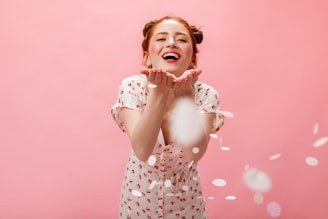 a woman in a polka dot dress blowing confetti