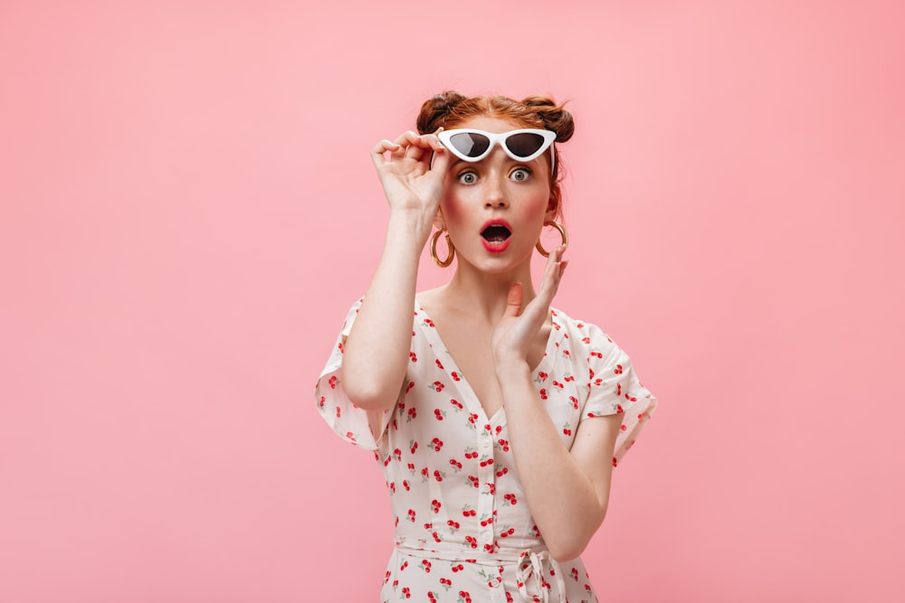 a woman in a dress and sunglasses making a funny face