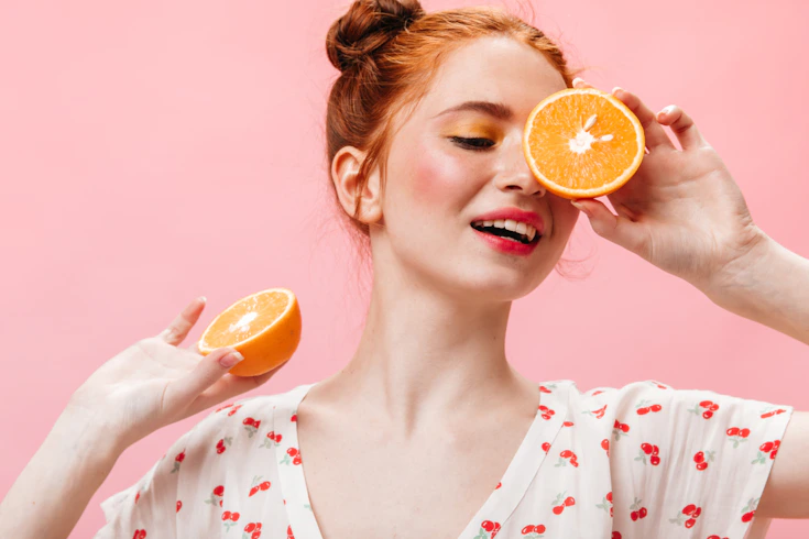 a woman holding an orange up to her eye