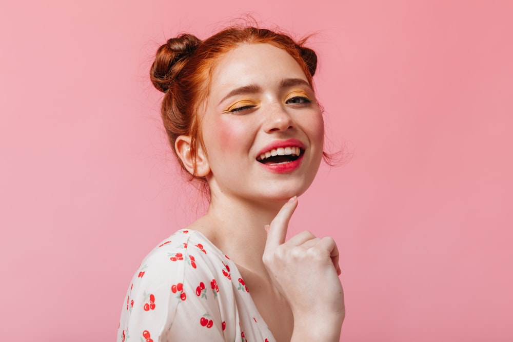a woman with red hair is smiling and holding her finger to her lips