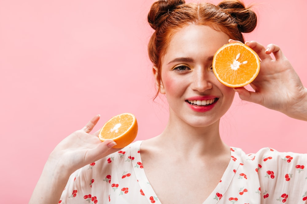 a woman holding two oranges up to her eyes