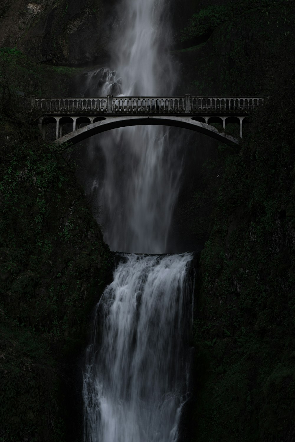 a large waterfall with a bridge over it