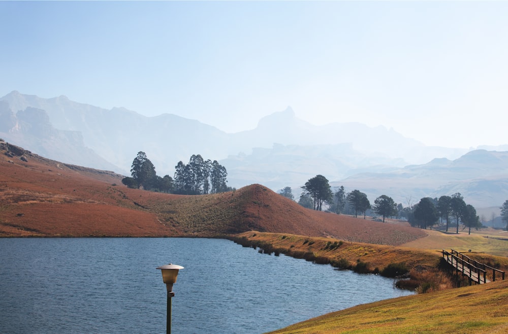 a lake in the middle of a field with mountains in the background