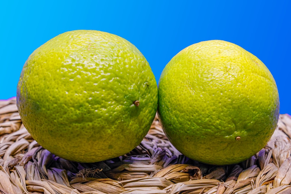 two limes sitting on top of a wicker basket