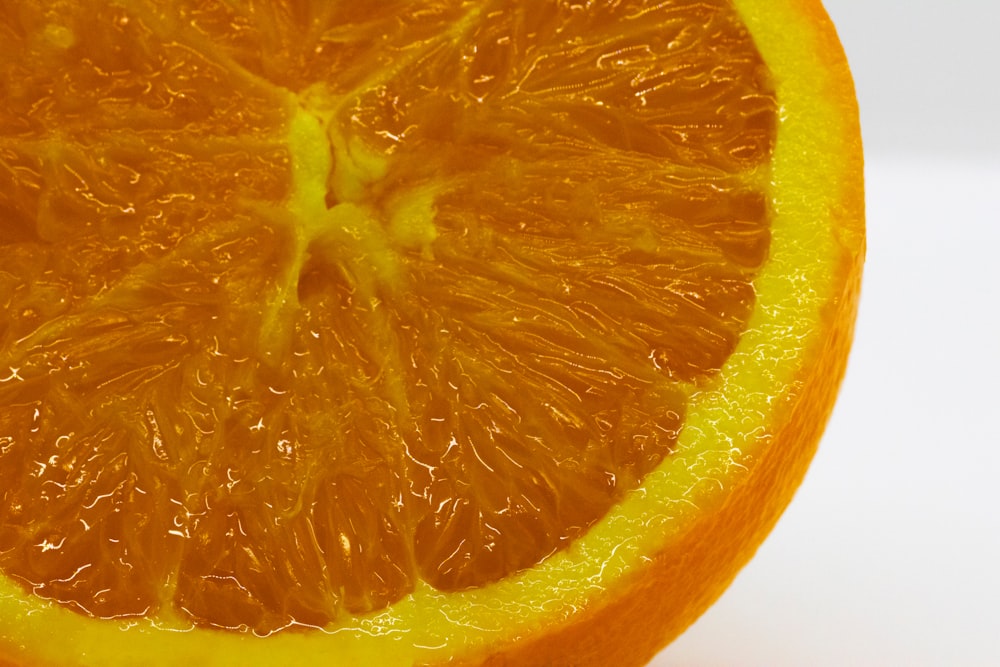 une orange coupée en deux sur une surface blanche