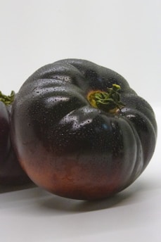 a couple of black tomatoes sitting on top of a white table