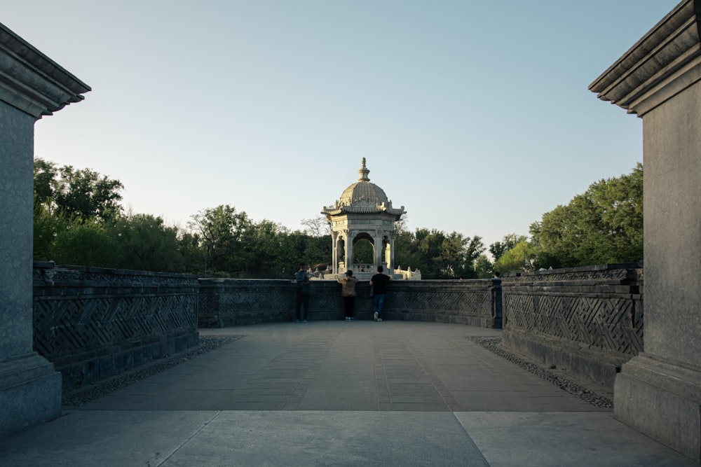 two people standing on a bridge with a gazebo in the background